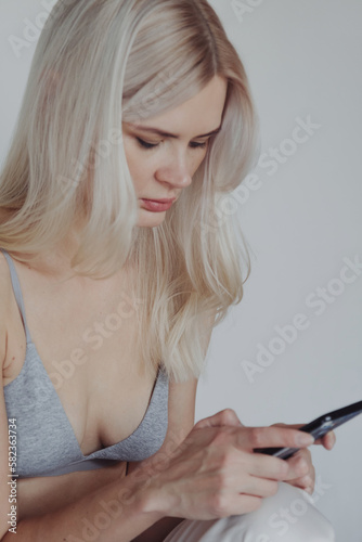 Blond woman in a bra with phone