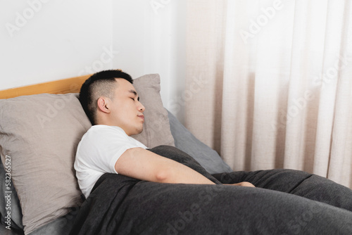 Asian man is sleeping in the bed. © Anciens