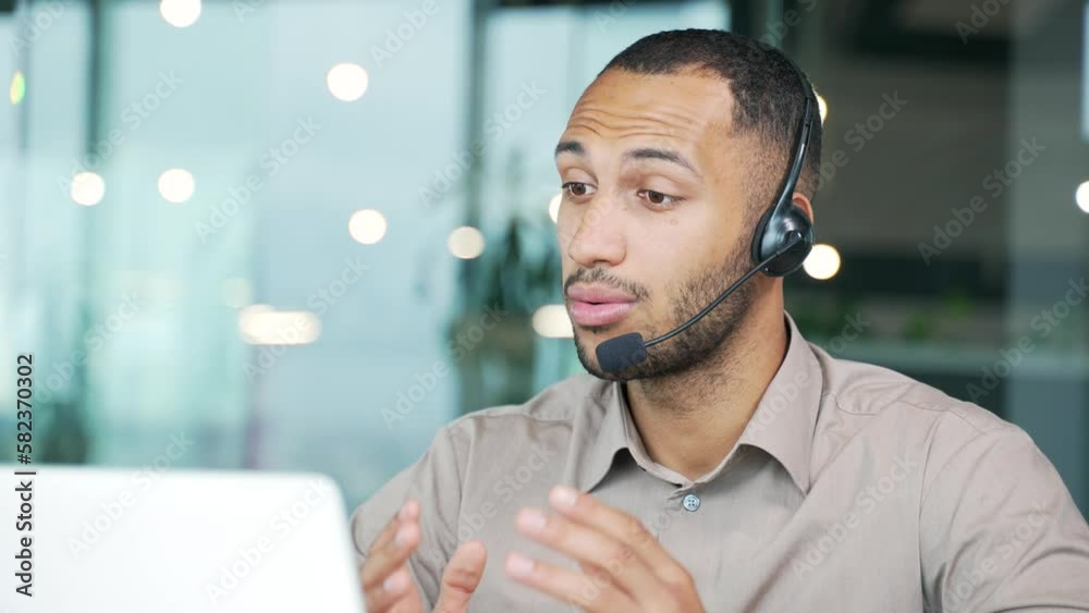 Close up. A corporate operator who works in customer support speaks on a video call using a laptop. Call center agent in wireless headset helping customer with complaints in office Online consultation