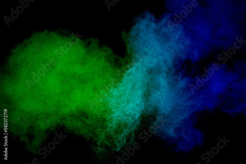 Green and blue powder explosion on black background.Freeze motion of green and blue dust cloud.