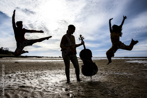 silhouetted dancers and cellist on Cape Cod beach