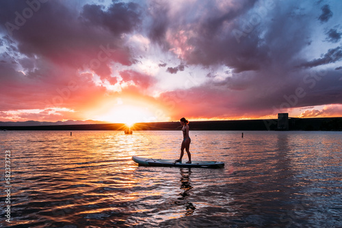 Teen paddle boarding at sunset photo