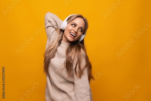 a girl with big headphones listens to her favorite music on a yellow background © Ivan Traimak