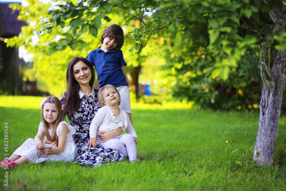 Young large family on a summer morning walk. Beautiful mother with children is playing in the park. Young large family on a summer morning walk. Beautiful mother with children is playing in the park.