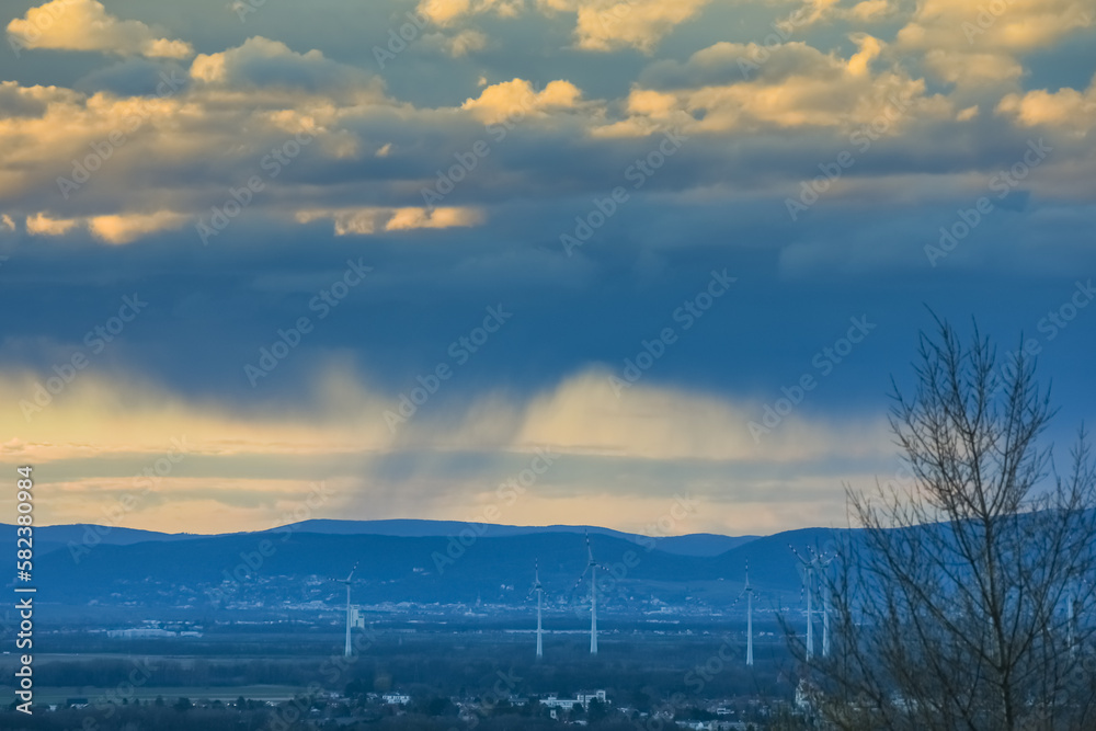 heavy rain under clouds during sundown in a landscape with windmills