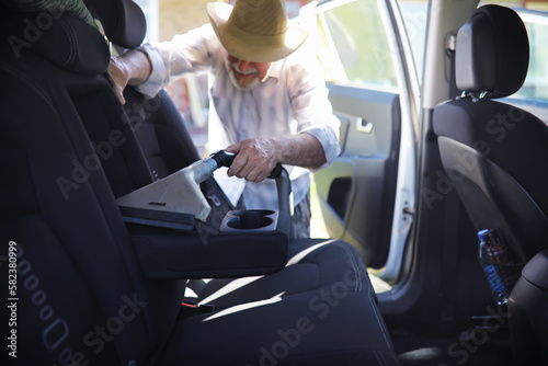 Grandfather cleaning car mats. Washing manual car. A gray-haired man cleans his car. © alexkich