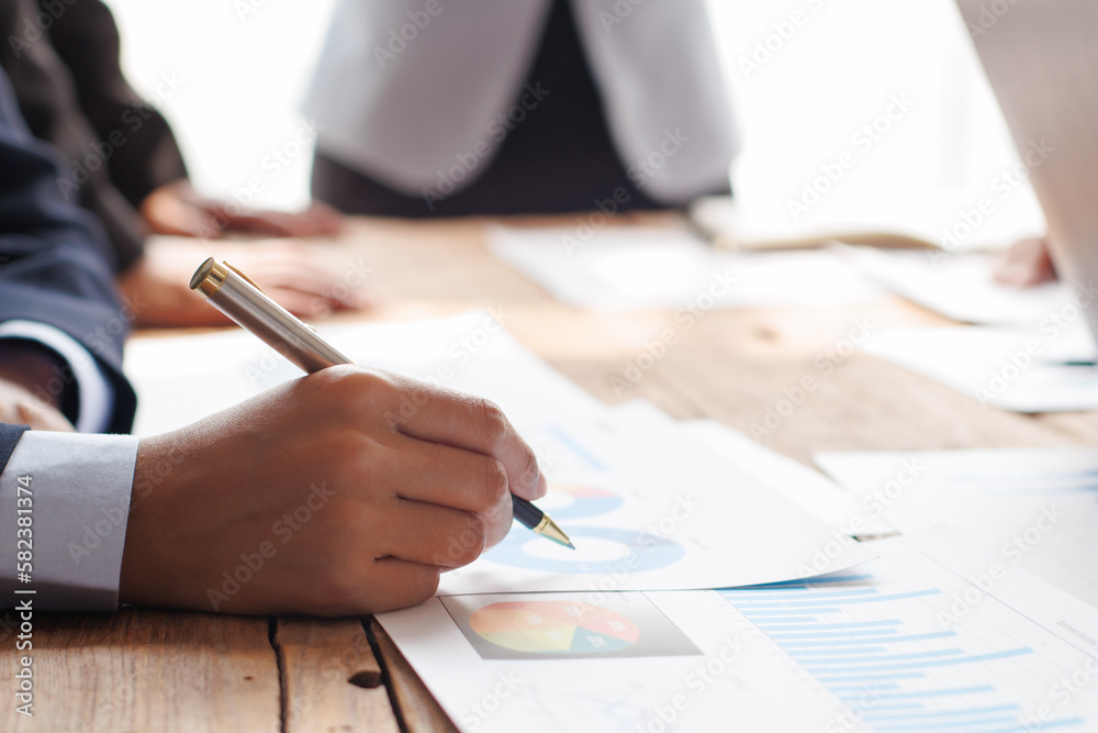 Fototapeta premium Teamwork with businessman analyzing cost graphs on table at conference room.