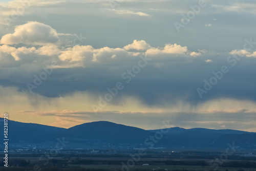 rain under clouds over a landscape with mountains