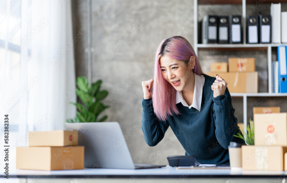 Portrait of an Asian businesswoman, a small business owner who successfully sells online and happily holds a smartphone with a laptop computer. Portrait of an Asian businesswoman, a small business owner who successfully sells online and happily holds a smartphone with a laptop computer.