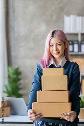 Portrait of a young Asian businesswoman sitting at a desk in an office recording data on a laptop. financial calculation and online delivery orders. © crizzystudio
