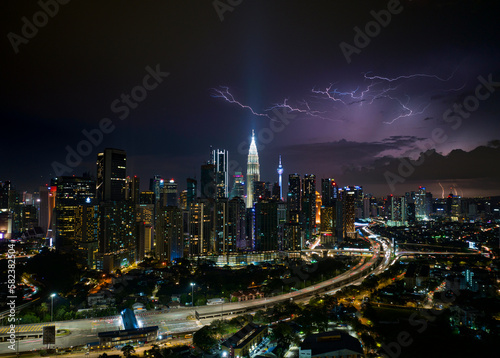 Aerial Panorama Kuala Lumpur cityscape during storm night with lightning strike above clouds photo
