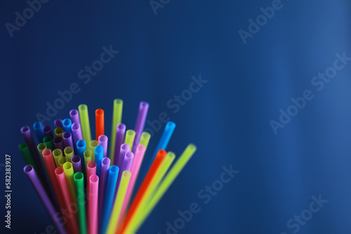 Colorful plastic drinking straws, close up as background. colored tubules for juice and cocktails on black wooden table