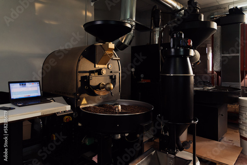 Professional machine in process of roasting and mixing coffee beans in modern industrial factory