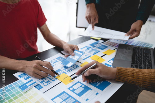 ux developers, UI designers Asian group data researchers brainstorm on tabletop mobile app interface wireframe design client summary color codes modern office Creative Digital Development Agency.