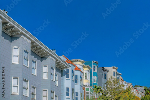 Colorful homes with panelled walls against blue sky in San Francisco California. Exterior view of beautiful multi-storey houses at a residential neighborhood on a sunny day.