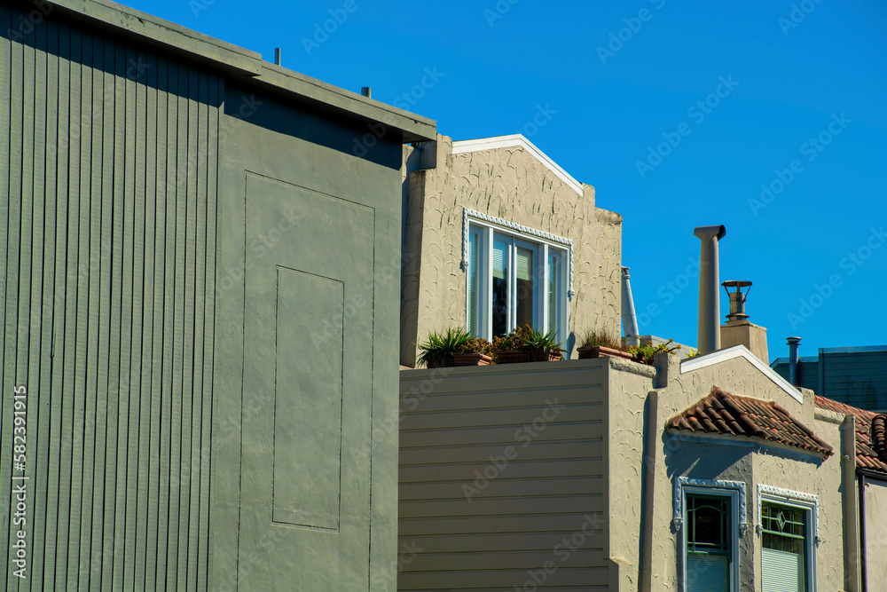 Row of houses with green flat modern design and beige or cream colored exterior visible chimney pipes and blue sky
