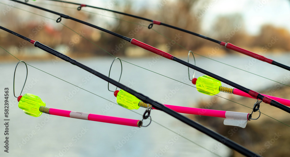 The bite alarm hangs on a fishing rod against the background of water. Fishing  rod while