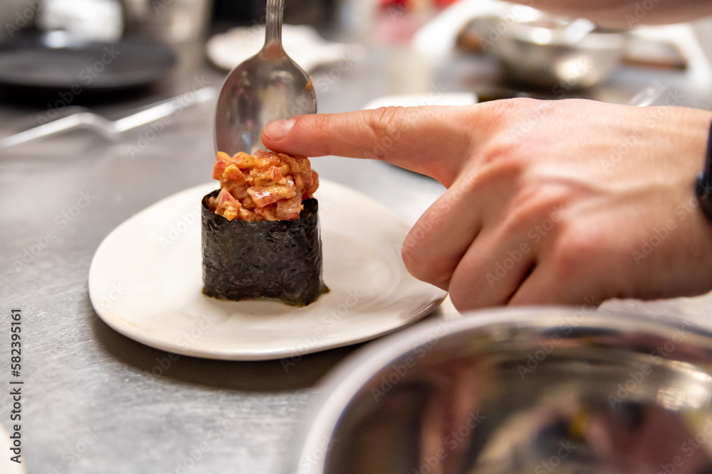 Chef's hands cooking gunkan sushi roll on kitchen