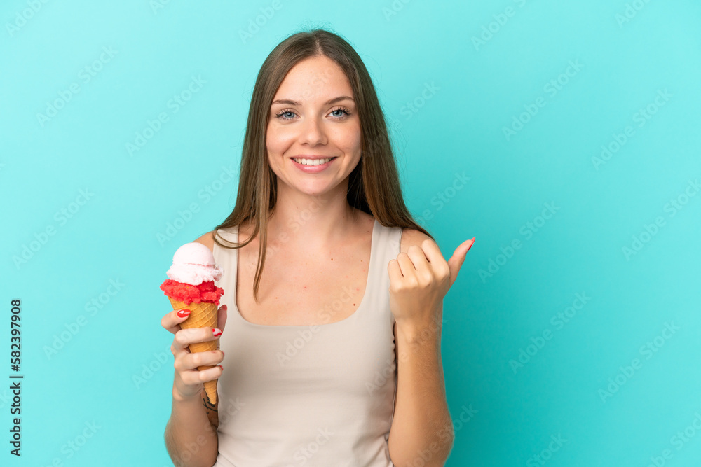Young Lithuanian woman with cornet ice cream isolated on blue background pointing to the side to present a product Young Lithuanian woman with cornet ice cream isolated on blue background pointing to the side to present a product