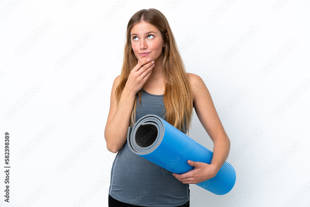 Young sport woman going to yoga classes while holding a mat looking up while smiling Young sport woman going to yoga classes while holding a mat looking up while smiling