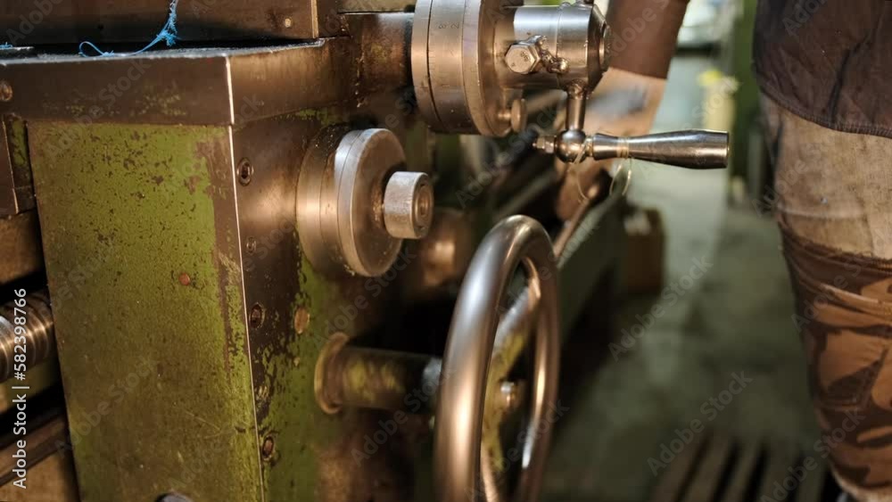 The hands of the worker change the parameters of the support of the lathe to move the cutter during the processing of the part. Close-up of a worker working on a lathe The hands of the worker change the parameters of the support of the lathe to move the cutter during the processing of the part. Close-up of a worker working on a lathe