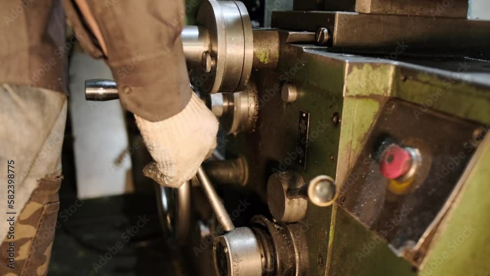 The worker's hands change the parameters of the lathe support to move the cutter during the processing of the part. Close-up of a worker working behind a lathe The worker's hands change the parameters of the lathe support to move the cutter during the processing of the part. Close-up of a worker working behind a lathe