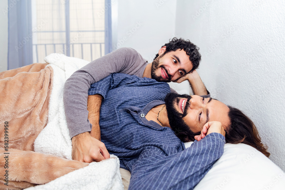gay male couple relaxing together at bed and smiling happy in the morning, concept of real people lifestyle and love between people of the same sex gay male couple relaxing together at bed and smiling happy in the morning, concept of real people lifestyle and love between people of the same sex