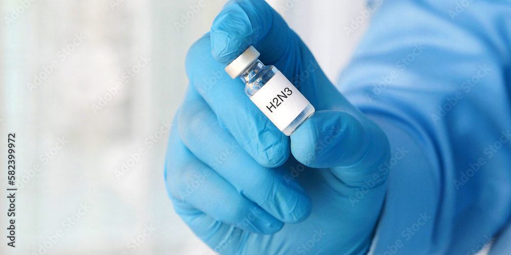 A doctor or health care worker or scientist's hand in gloves holding the H3N2 influenza virus vaccine, closeup. Health and medicine concept.