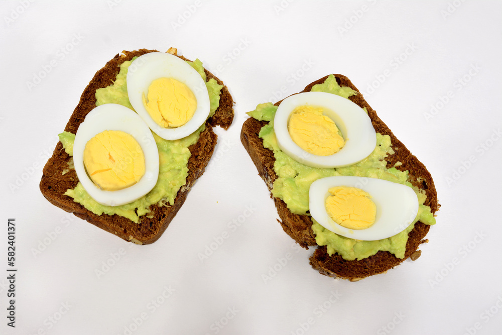 A sandwich with avocado and hard boiled eggs with yellow yolks isolated on white background A sandwich with avocado and hard boiled eggs with yellow yolks isolated on white background