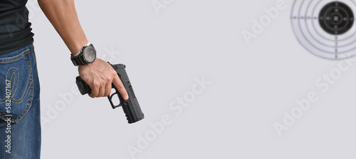 A gun shooter holds 9mm automatic pistol in right hand in front of the gun shooting range, concept for security, robbery, gangster and bodyguard training around the world. selective focus on pistol.