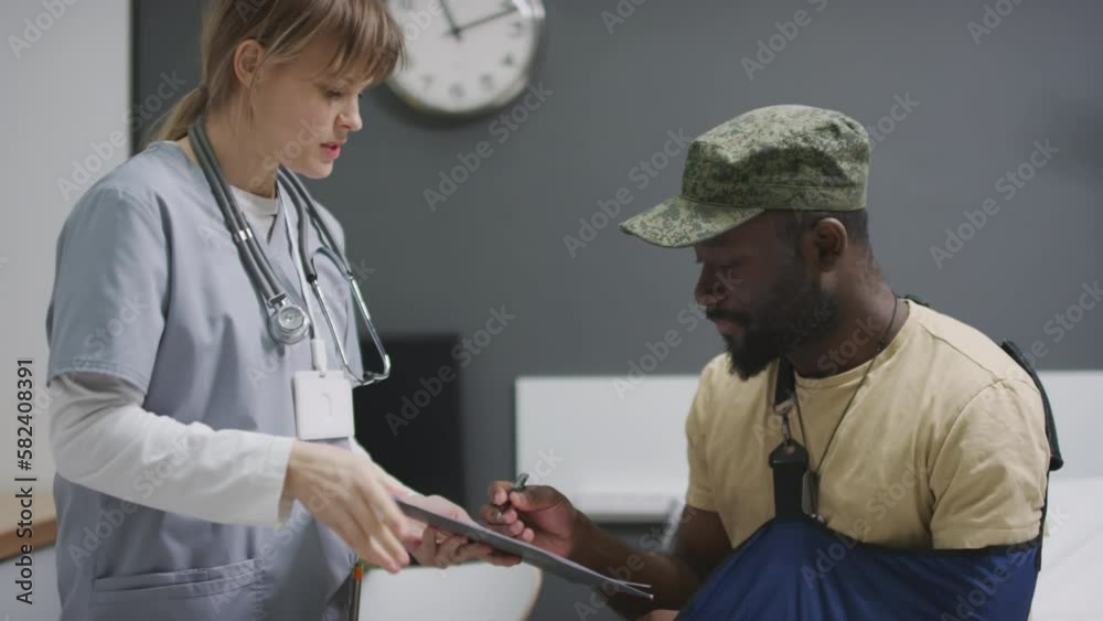 African American soldier signing paper to get discharged from military hospital and doing handshake with doctor