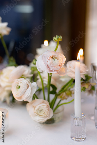 Banquet table decorated with plates, cutlery, candles, glasses and flower arrangements