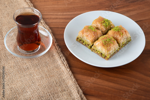 Traditional pistachio baklava with Turkish tea.A plate of baklava on wooden table
