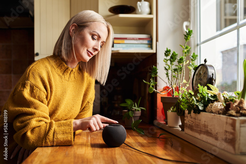 Adult woman using smart speaker on kitchen counter photo