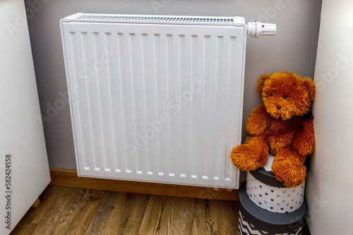 A brown teddy bear placed near a radiator as an energy concept in the world. Problems of adults affecting children's life and development. 