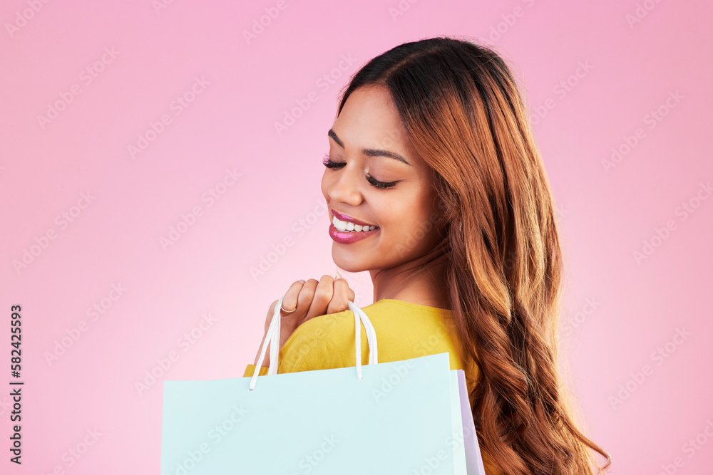 Fototapeta premium Woman, shopping bag and smile in studio with a customer happy about promotion or discount. Female model or shopper on a pink background for fashion, sale and gift or surprise in mockup paper bags