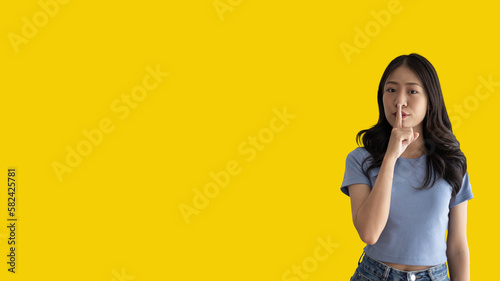 фотографія Asian woman doing silent gesture with finger, Noiseless symbol, Noisy mall, Hide a secret, Do not speak