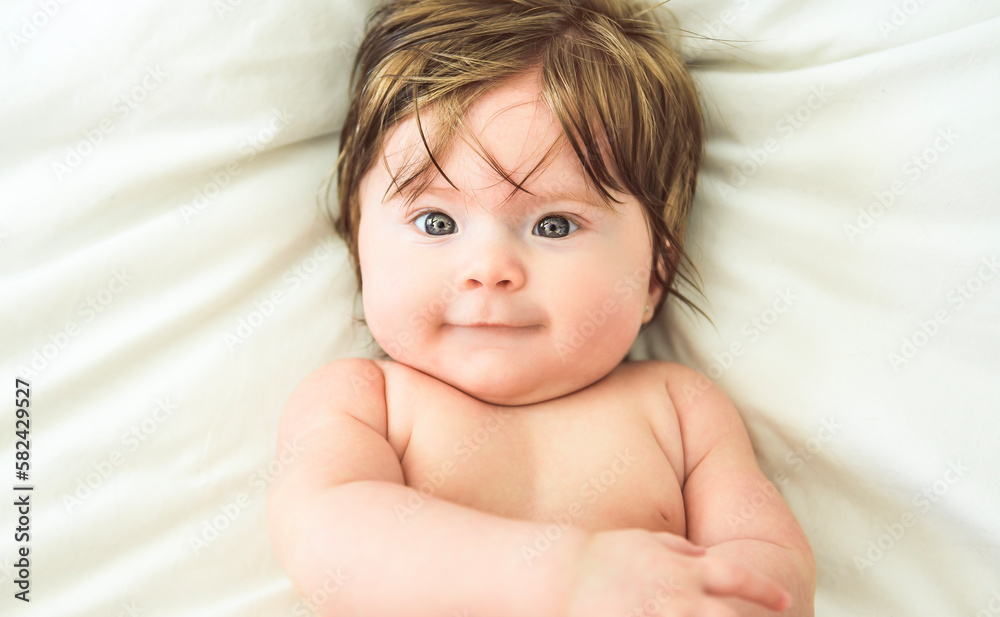 Portrait of cute adorable white Caucasian baby girl lay on a white bed Portrait of cute adorable white Caucasian baby girl lay on a white bed