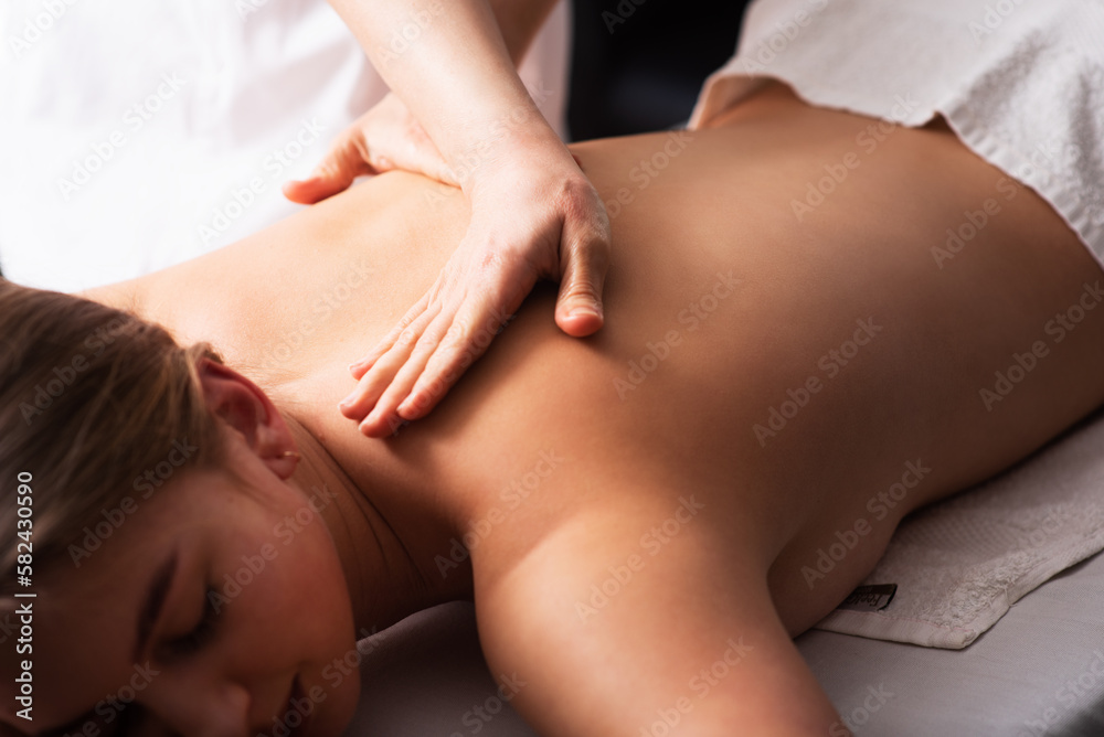 masseur massaging back and shoulder blades of young woman on massage table. Concept of massage spa treatments. Close-up