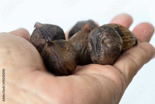Close-up shot of black garlic lying on someone hand.