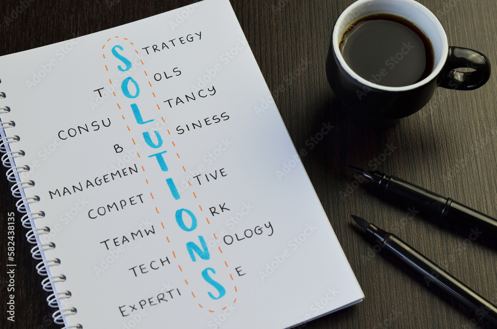 SOLUTIONS crossword handwritten in notebook with cup of coffee and pens on desk SOLUTIONS crossword handwritten in notebook with cup of coffee and pens on desk