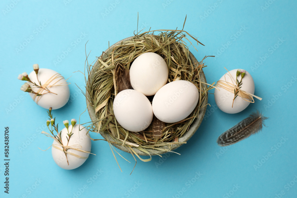 Nest with chicken eggs and natural decor on light blue background, flat lay. Happy Easter Nest with chicken eggs and natural decor on light blue background, flat lay. Happy Easter