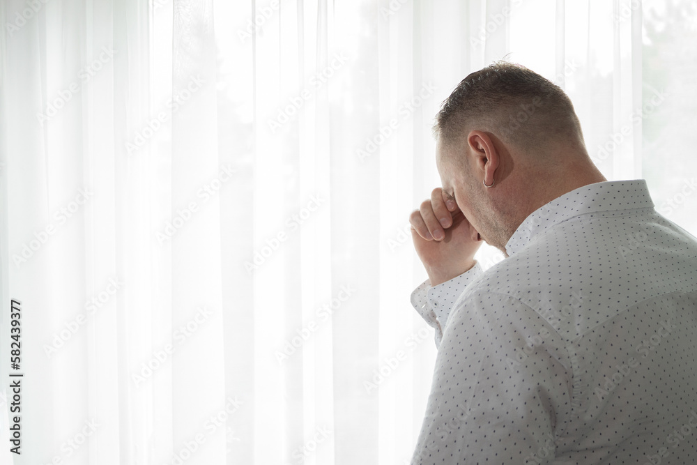 Fototapeta premium A modern man mourns while standing at the window