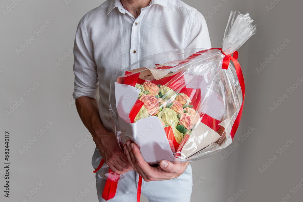 Faceless man holds bouquet marshmallow sweet flowers in hands. Gift in red wrapper with delicate sugarless roses on light background. Small business home. Hobby baking. Holiday gift. Homemade present Faceless man holds bouquet marshmallow sweet flowers in hands. Gift in red wrapper with delicate sugarless roses on light background. Small business home. Hobby baking. Holiday gift. Homemade present
