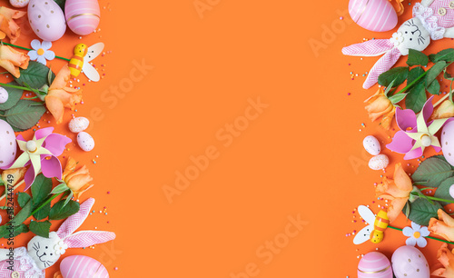 Photography easter frame with fresh spring carrots ,easter eggs,confetti,decor on an orange background