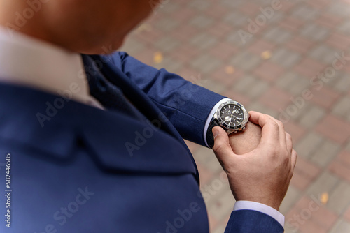 A man in a suit is checking his watch.