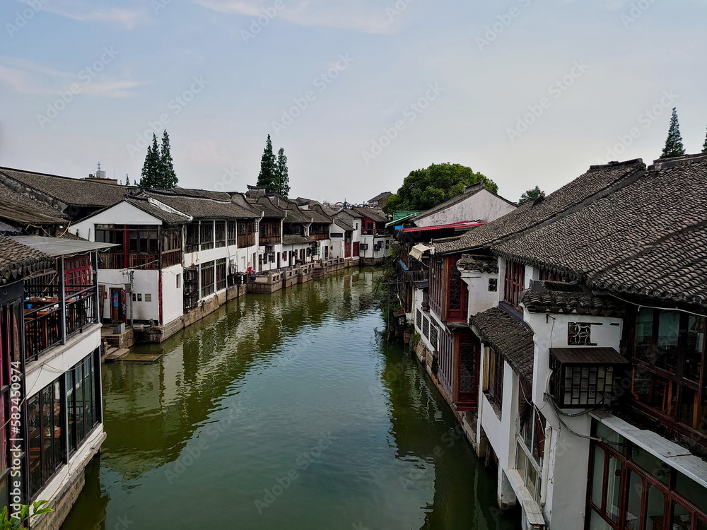 Shanghai, China - Jul 25, 2019: A view of the riverside of Zhujiajiao, a traditional Chinese town, from a bridge of its riverside architecture before the pandemic under bright blue sky on a summer day