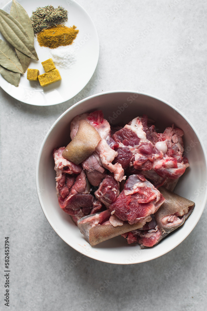 Fresh raw goat meat in a white bowl, chopped goat meat being prepared for cooking