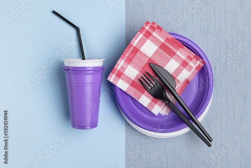 A set of plastic tableware and cutlery on a gray background. Studio shot, close-up.
