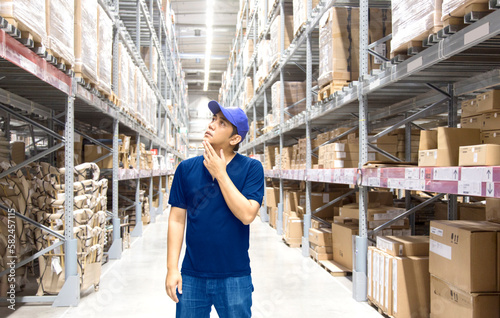 Asian man finding goods on stock shelves by himself in warehouse in logistic business concept